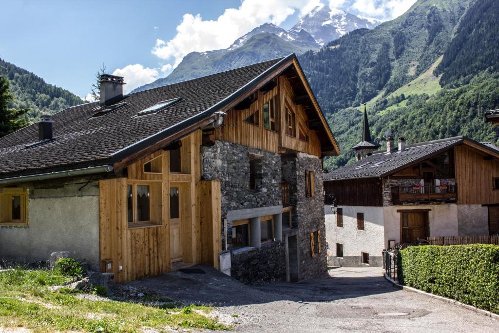 a house with wooden doors and mountains in the background at Le Thuria in Sainte-Foy-Tarentaise