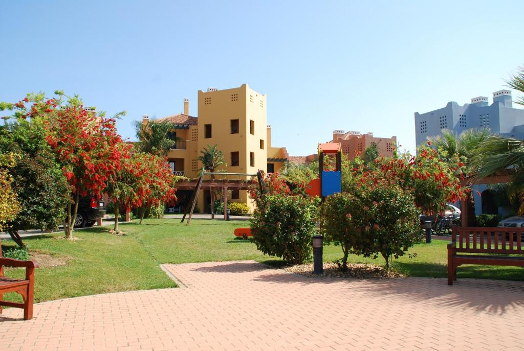 イスラ・カネラにあるEl Rincón del Golf II by HOMAのベンチや花の木々や建物のある公園