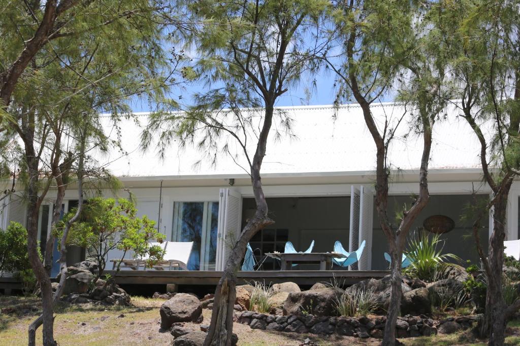 una casa con terraza, sillas y árboles en Bakwa Lodge en Rodrigues Island