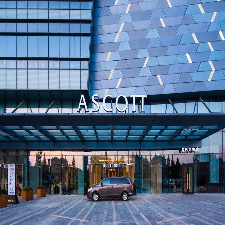 un'auto parcheggiata in un parcheggio di fronte a un edificio di Ascott Harmony City Nantong a Nantong
