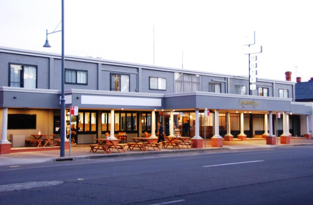 a building with tables and benches on a city street at Commodore Motor Inn in Albury