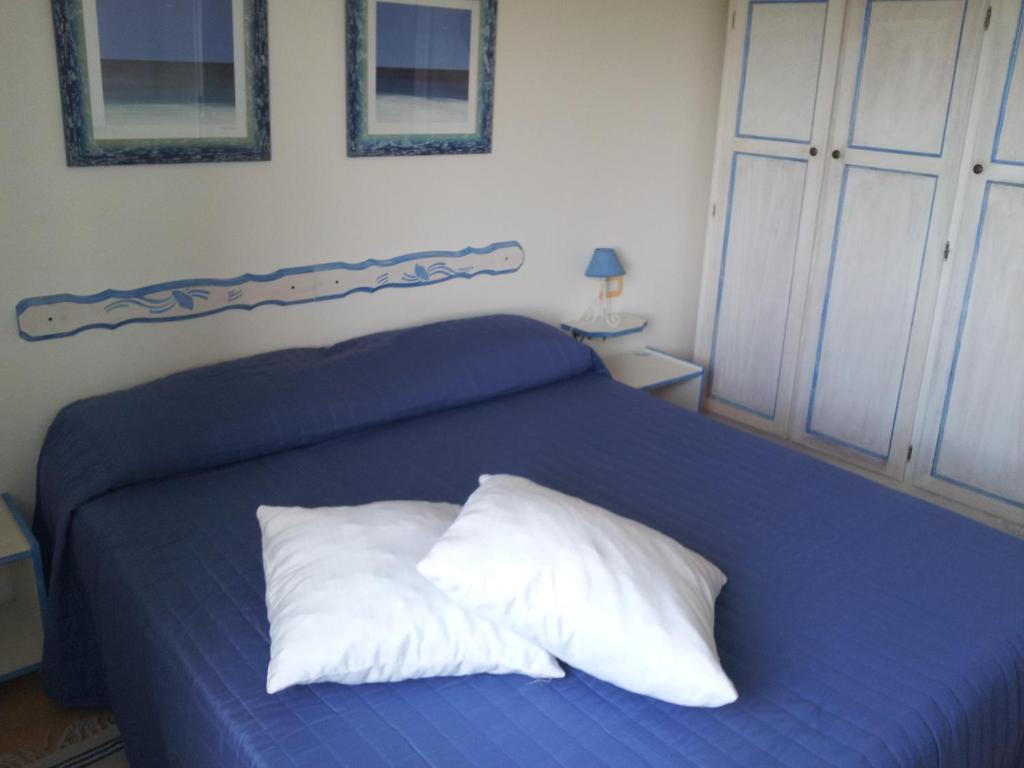 niebieskie łóżko z białą poduszką w obiekcie Sardegna casa al mare San Teodoro Vaccileddi Porto San Paolo w mieście Porto San Paolo