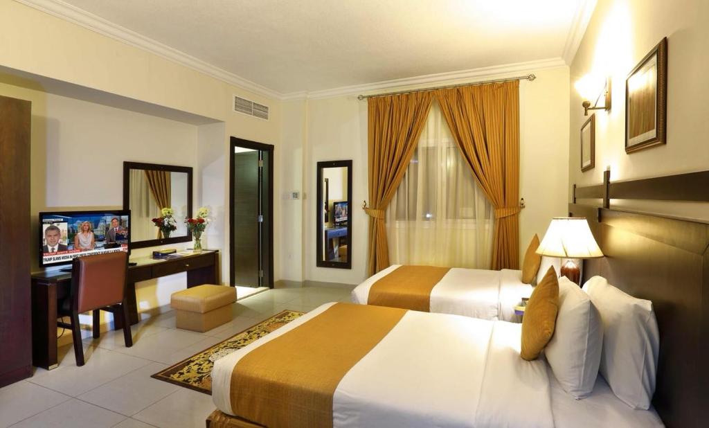 a hotel room with two beds and a desk at Al Hayat Hotel Suites in Sharjah