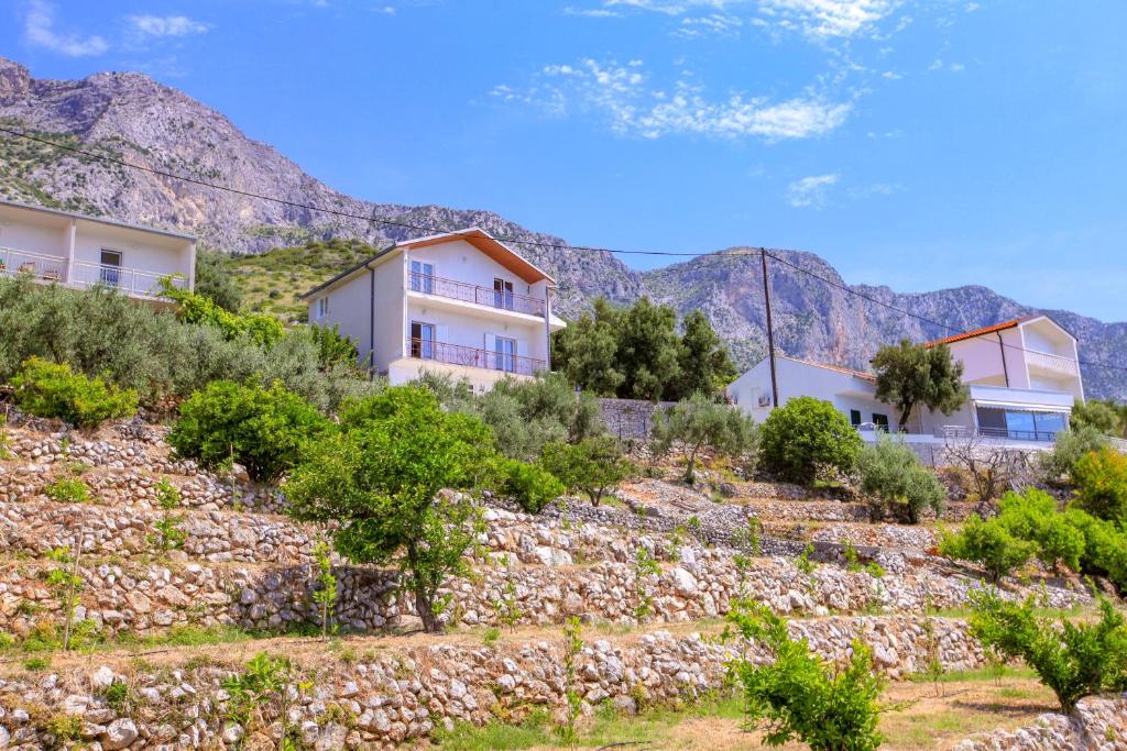 a house on a hill with mountains in the background at Apartments Gaspar in Podaca