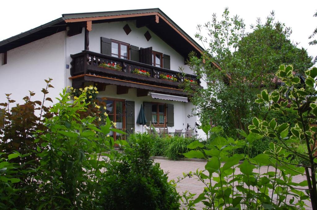 ein weißes Haus mit einem Balkon und einigen Bäumen in der Unterkunft Ferienwohnung Haus Alpenrebe in Schönau am Königssee