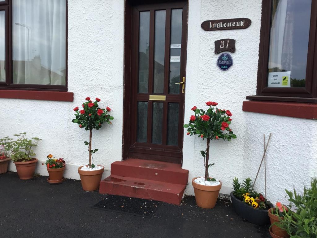 uma porta de uma casa com vasos de plantas em frente em Ingleneuk Bed and Breakfast em Edinburgo