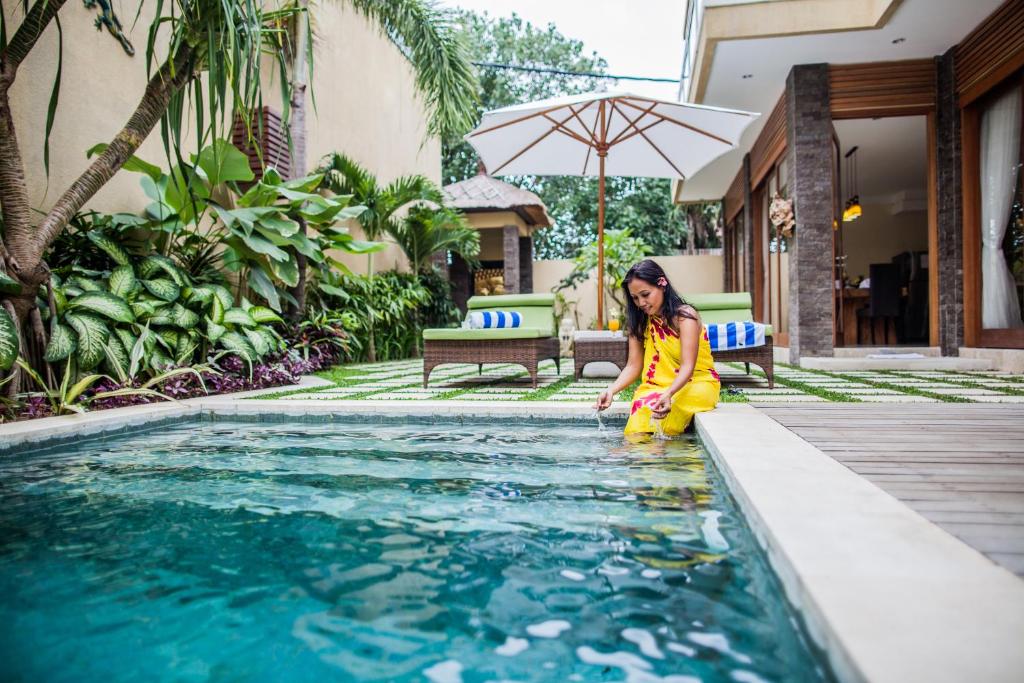 a little girl sitting next to a swimming pool at O Villas Seminyak in Seminyak