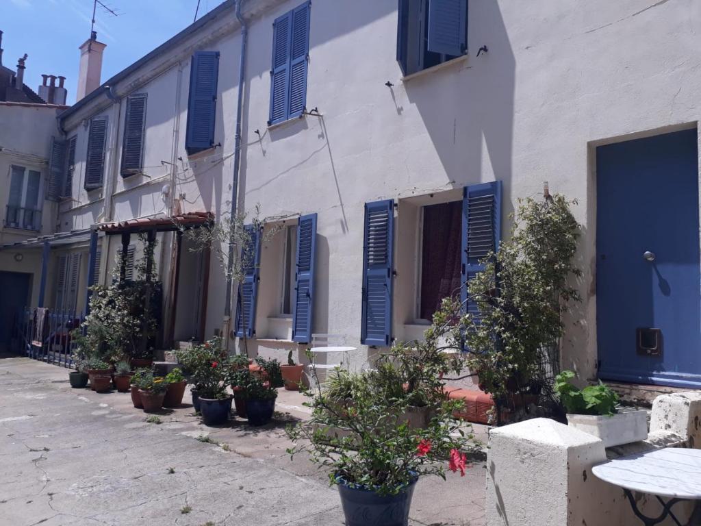 eine Straße mit blauen Fensterläden und Topfpflanzen in der Unterkunft Le Tivoli in Cannes