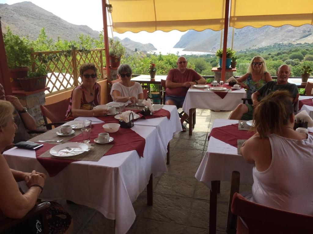 eine Gruppe von Personen, die in einem Restaurant an Tischen sitzen in der Unterkunft Taxiarchis in Symi