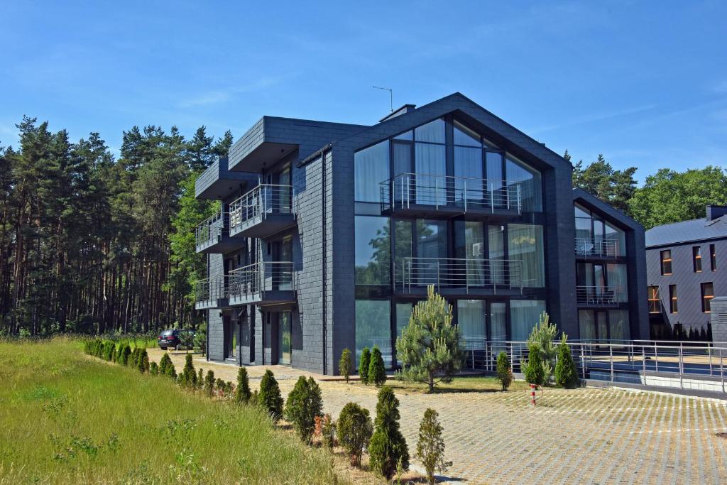 une maison moderne avec des baies vitrées et des arbres dans l'établissement Smilčių Apartment, à Palanga
