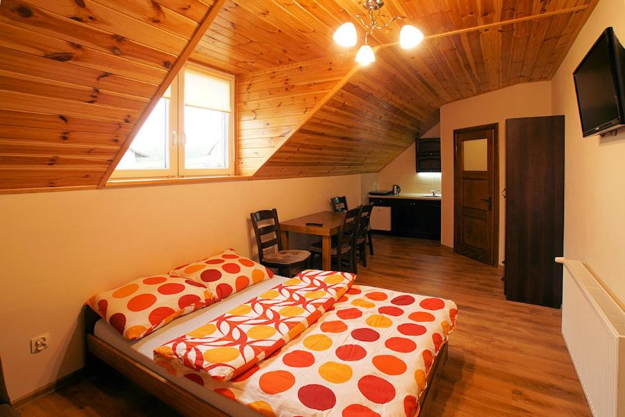 Noclegi Azyl في Krajno-Zagórze: سرير كبير في غرفة ذات سقف خشبي