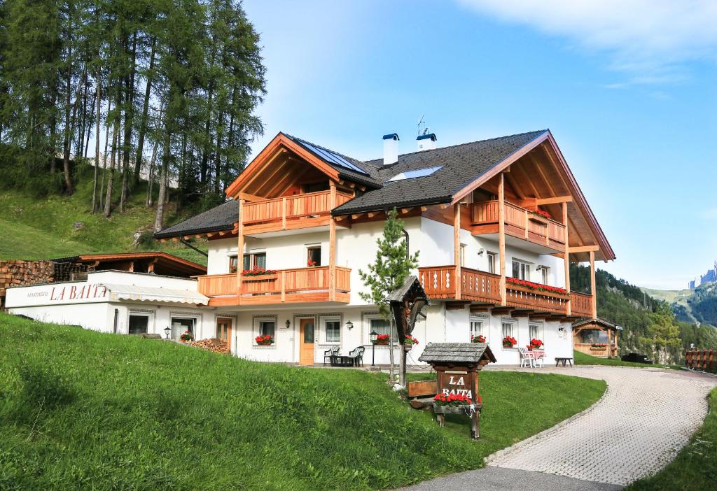 a large white building with wooden balconies on a hill at Apartments La Baita in Santa Cristina Gherdëina