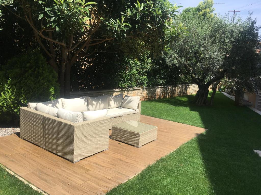 a white couch sitting on a wooden deck in a yard at Apartmani Žužić in Poreč