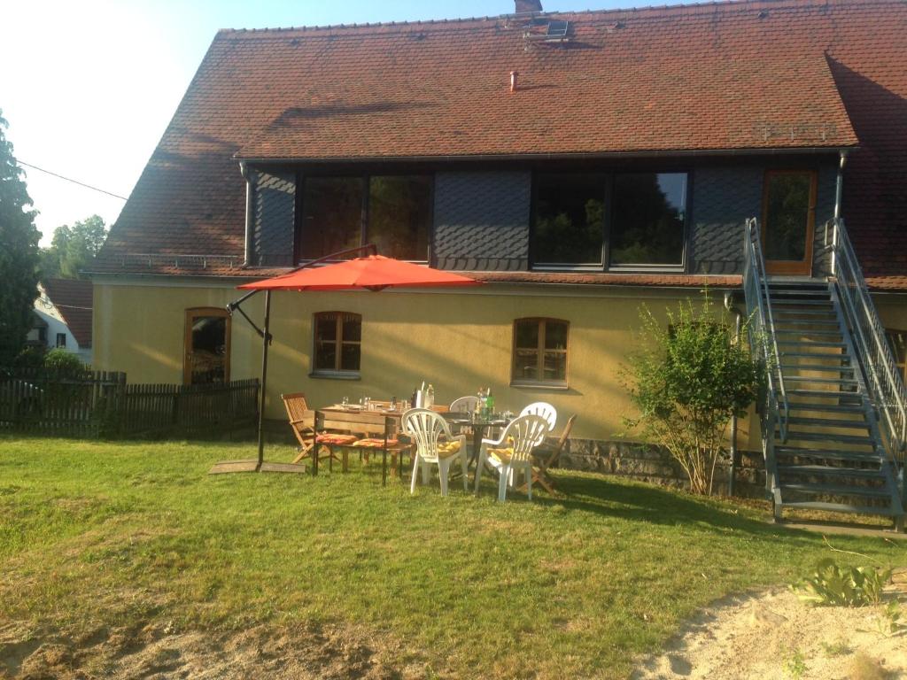 ein Haus mit einem Tisch und Stühlen im Hof in der Unterkunft Moderne Pension vonBartsch mit Ladestation in der sächsischen Schweiz in Struppen