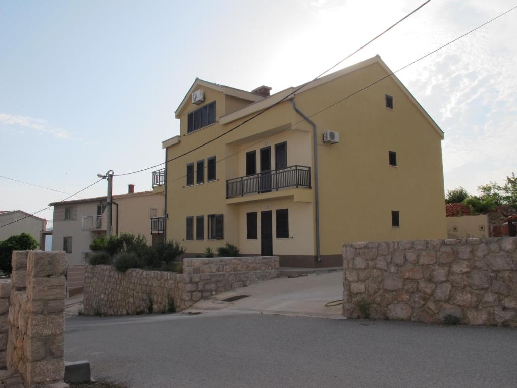 a large yellow building with a stone wall at Apartmani Stille in Karlobag