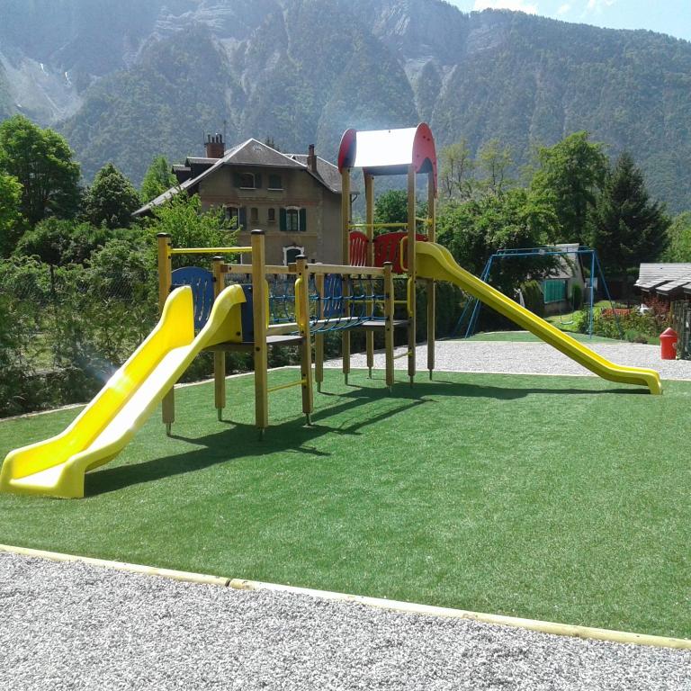 - une aire de jeux avec toboggan sur l'herbe dans l'établissement A La Rencontre Du Soleil - Camping, au Bourg-dʼOisans
