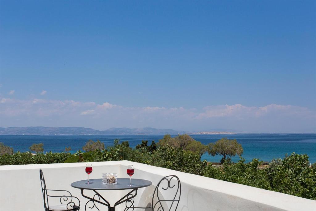 アイギナにあるAneli Luxury Villas-Villa Aeginaのテーブルと椅子、海の景色を望むバルコニー