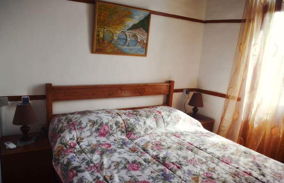 a bedroom with a bed with a floral comforter on it at Guest House Vasili in Berat