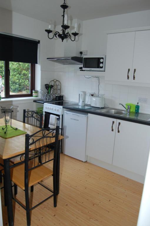 a kitchen with white cabinets and a wooden table at Inisfail in Killarney