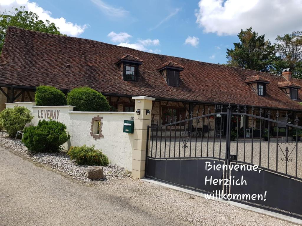 a building with a fence with a sign in front of it at Le Venay in Frontenaud