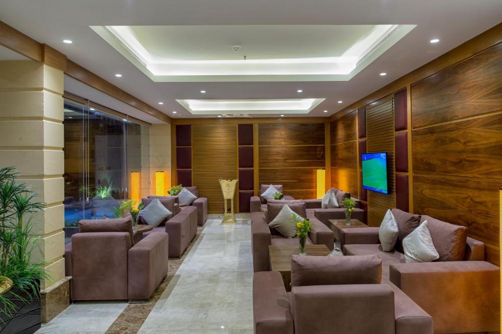 una sala de espera con sillas de cuero marrón y TV en Classical Hotel Suites, en Yeda