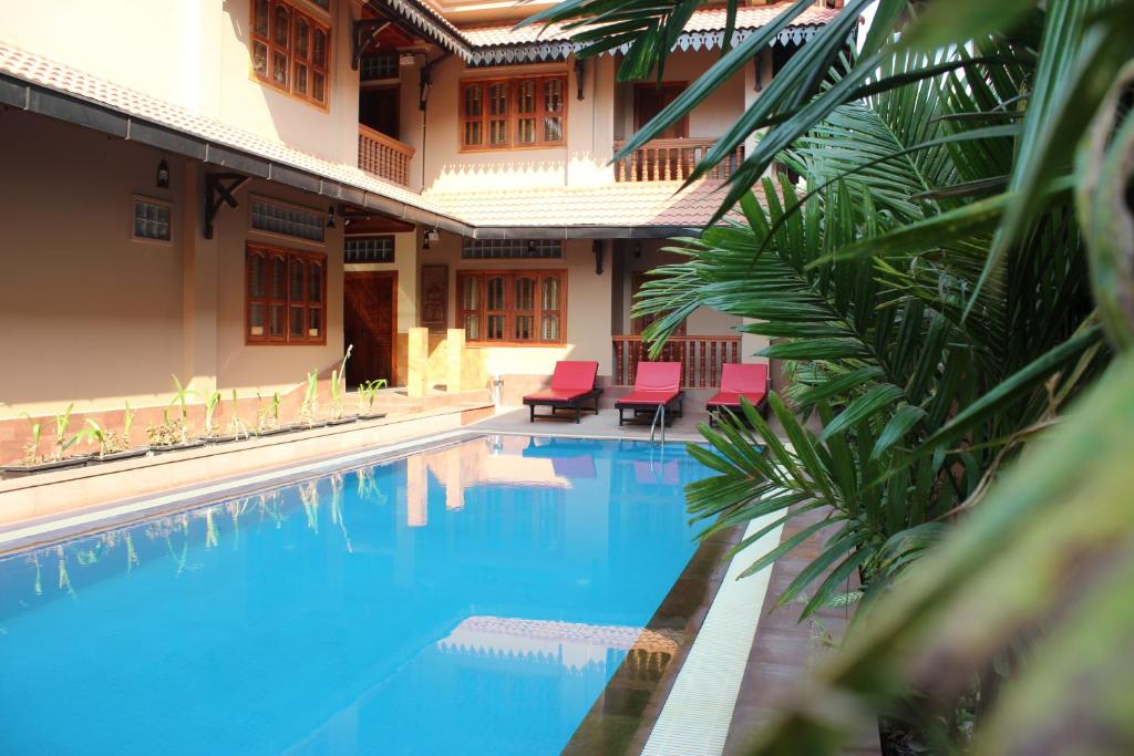 a swimming pool with red chairs and a building at Shining Angkor Apartment Hotel in Siem Reap