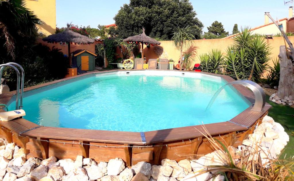une grande piscine entourée d'un banc en bois. dans l'établissement Gite Saint Julien, à Argelès-sur-Mer