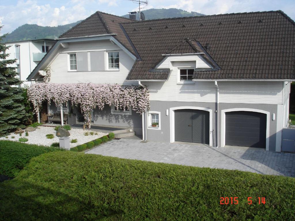 a white house with a flowering tree in front of it at Ferienwohnung Grienwald in Dornbirn