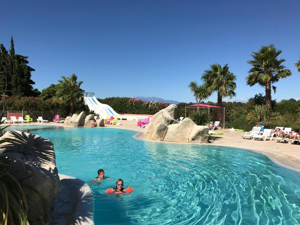 two people swimming in a pool at a resort at Camping Le Méditerranée Argelès - Domaine piétonnier in Argelès-sur-Mer