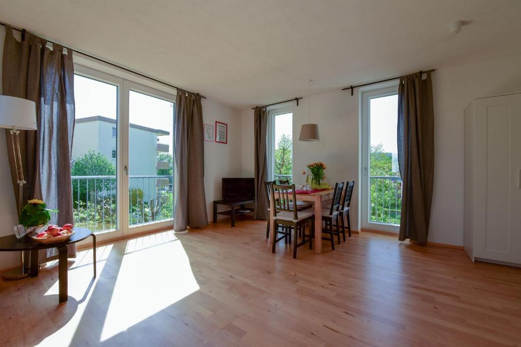 a living room with a table and chairs and large windows at FeWo Seeblüte in Oberteuringen