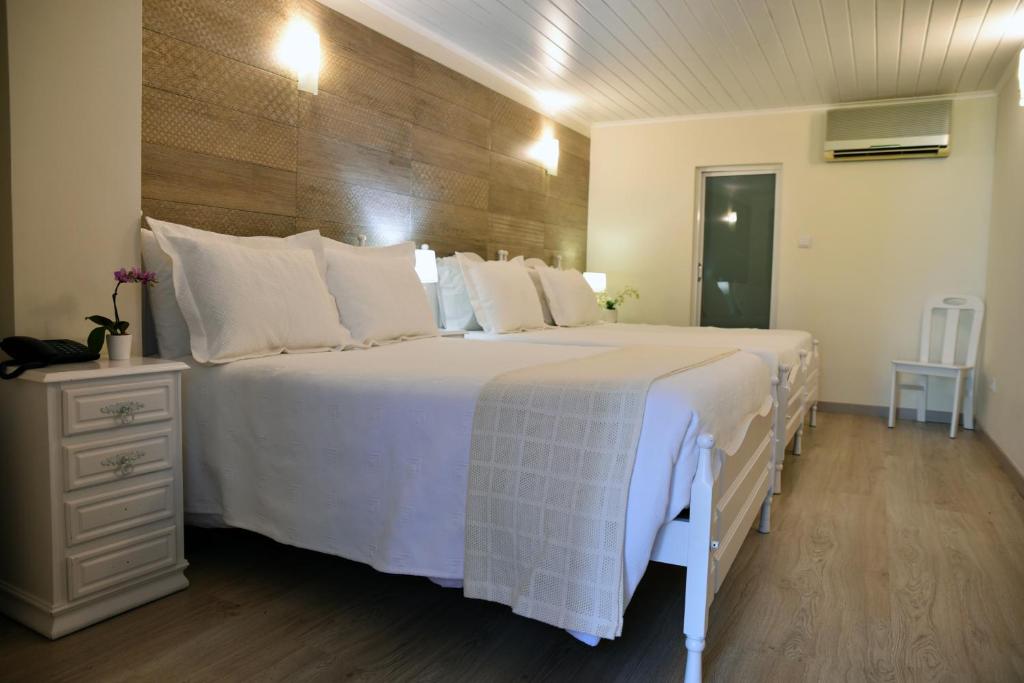 um quarto com uma cama grande e almofadas brancas em Hotel Visconde em Porto