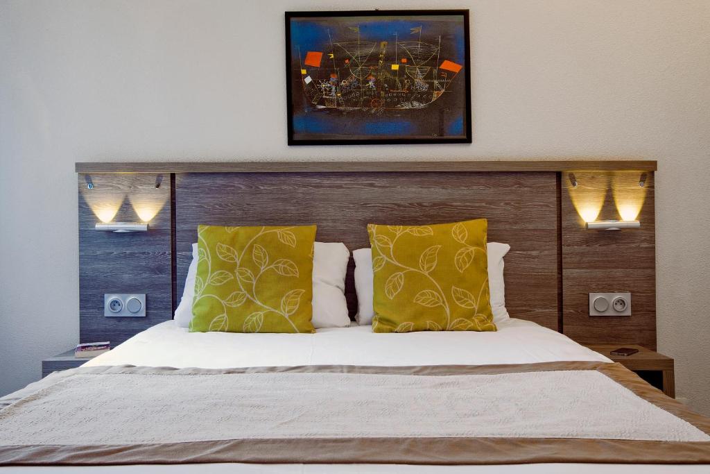 Un dormitorio con una cama grande con almohadas amarillas. en Séjours & Affaires Clermont Ferrand Park République, en Clermont-Ferrand