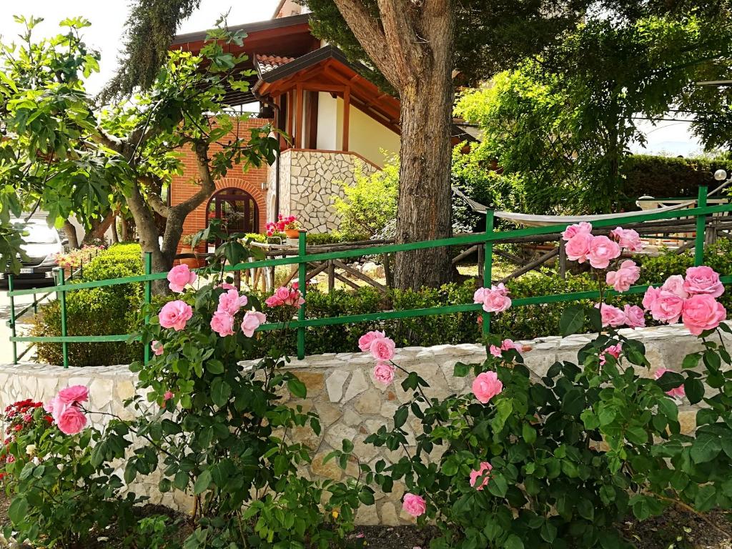 einen grünen Zaun mit rosa Rosen vor einem Haus in der Unterkunft La dimora di Radha B&B Centro Olistico in Rende