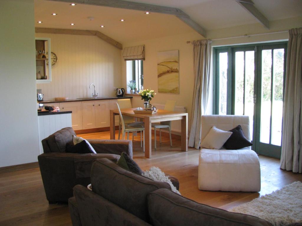 a living room with two couches and a table and a kitchen at The Granary at Cornish Barn Holidays in Truro