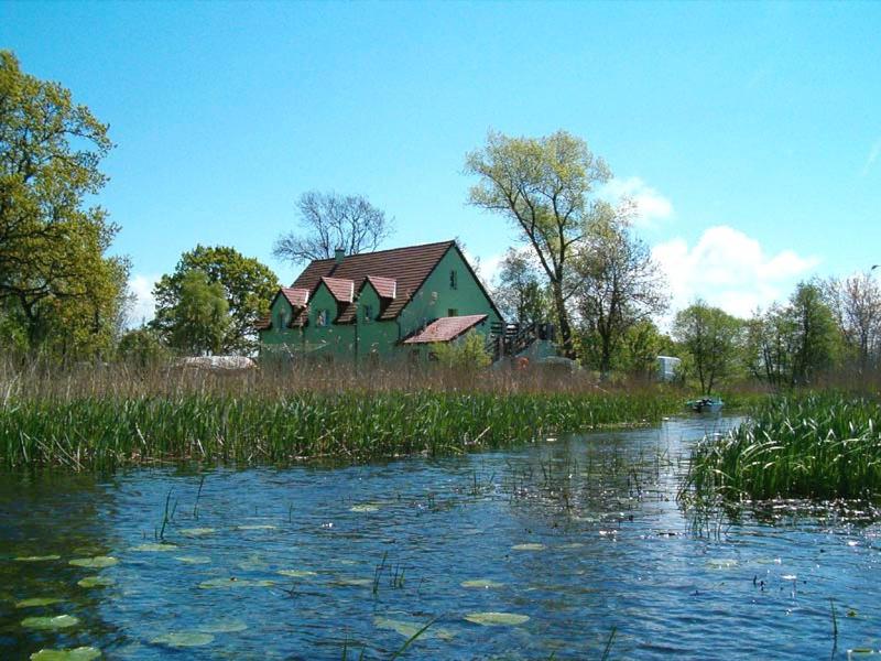 a green house is sitting next to a river at Green Gables in Mrzeżyno