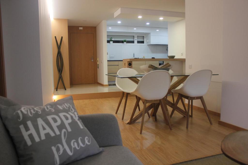 a living room with a table and chairs and a kitchen at Apartamento Milénio T2 in Arouca