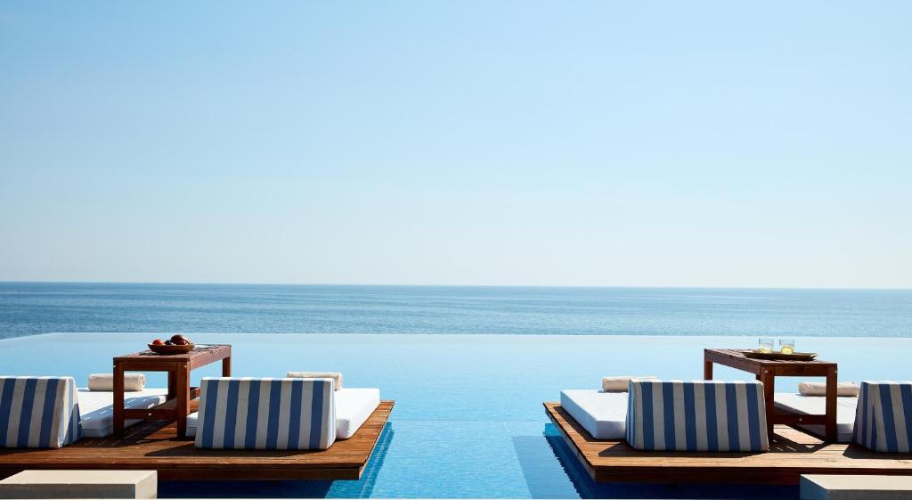 - une piscine avec des chaises et des tables dans l'eau dans l'établissement Cavo Olympo Luxury Hotel & Spa - Adult Only, à Plaka Litochorou