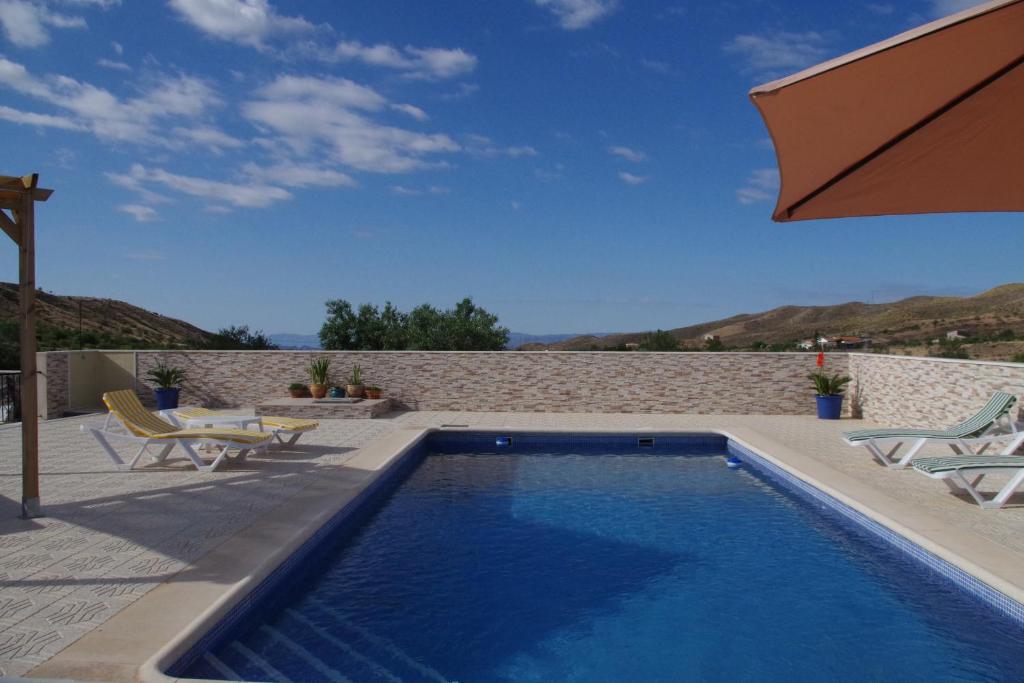 a swimming pool with two chairs and an umbrella at Casa Leonora in Huércal-Overa