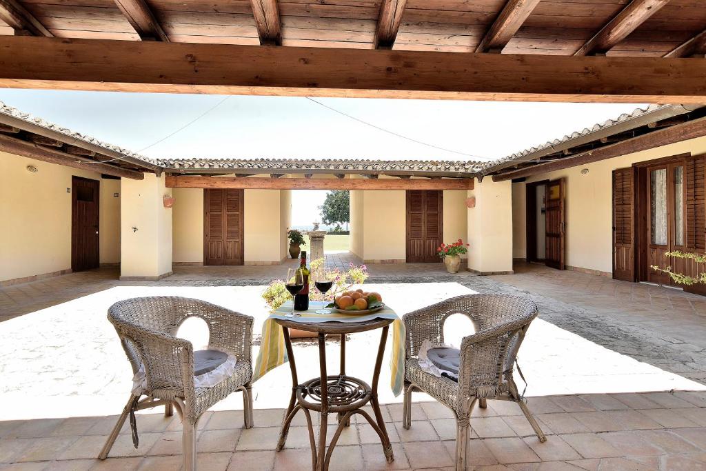 een patio met een tafel met 2 stoelen en een fles wijn bij Villa Giannina in Ispica