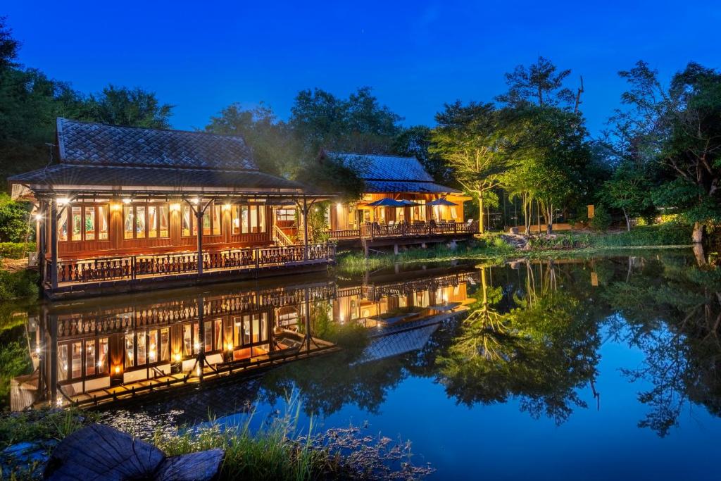 een huis op het water 's nachts bij Vana Varin Resort in Hua Hin