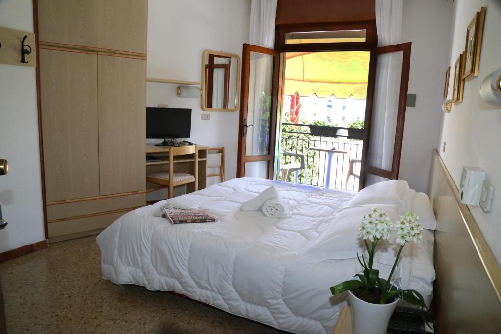 a bedroom with a large white bed with a window at Hotel Berna in Eraclea Mare