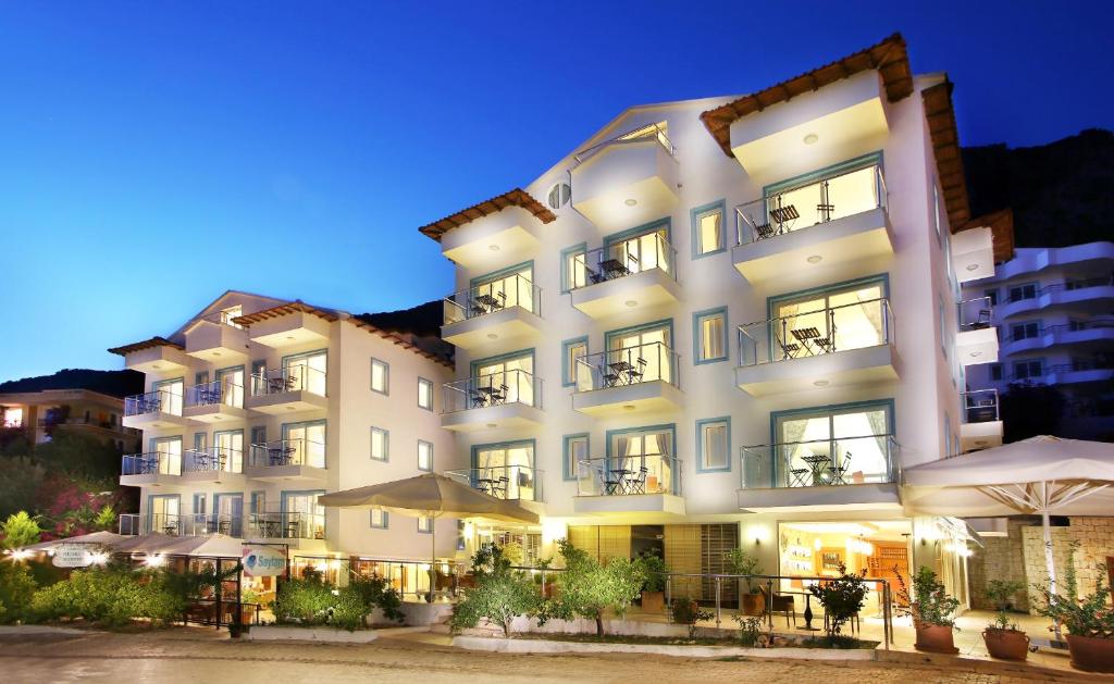 a large white building with tables and umbrellas at Saylam Suites in Kaş