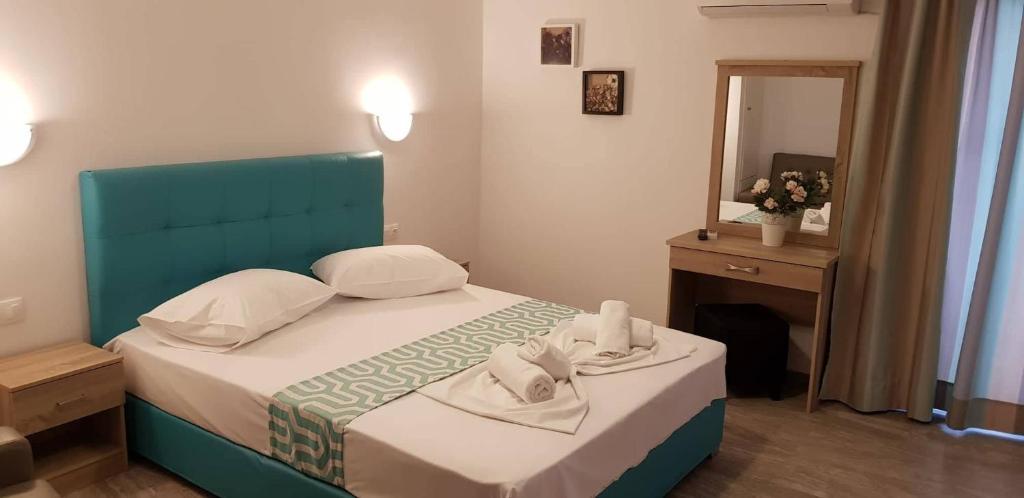 Schlafzimmer mit einem Bett mit blauem Kopfteil und einem Spiegel in der Unterkunft Cielo Apartments in Poros
