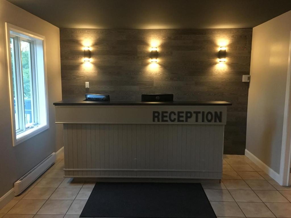 a reception desk in a room with lights on the wall at Auberge Valcartier in Saint-Gabriel-De-Valcartier