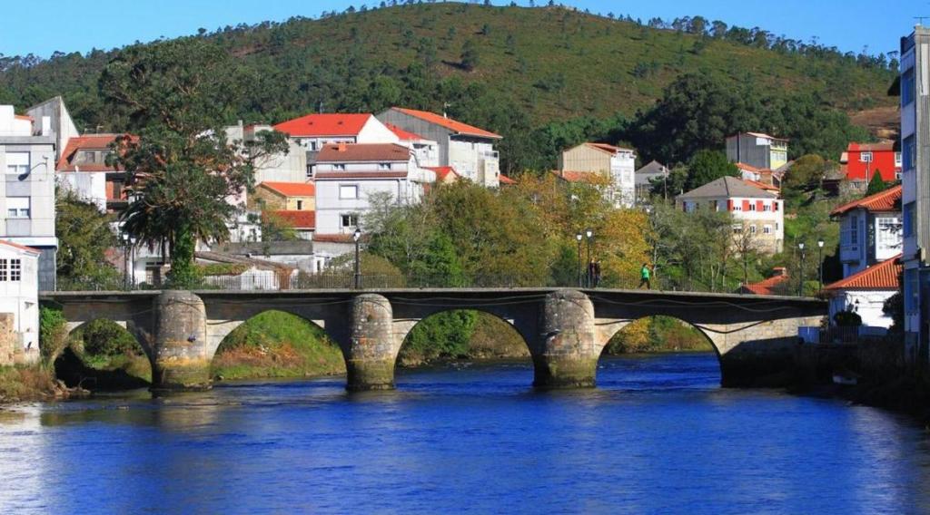 un puente sobre un río en una ciudad con edificios en Hostal O Pincho, en A Ponte do Porto