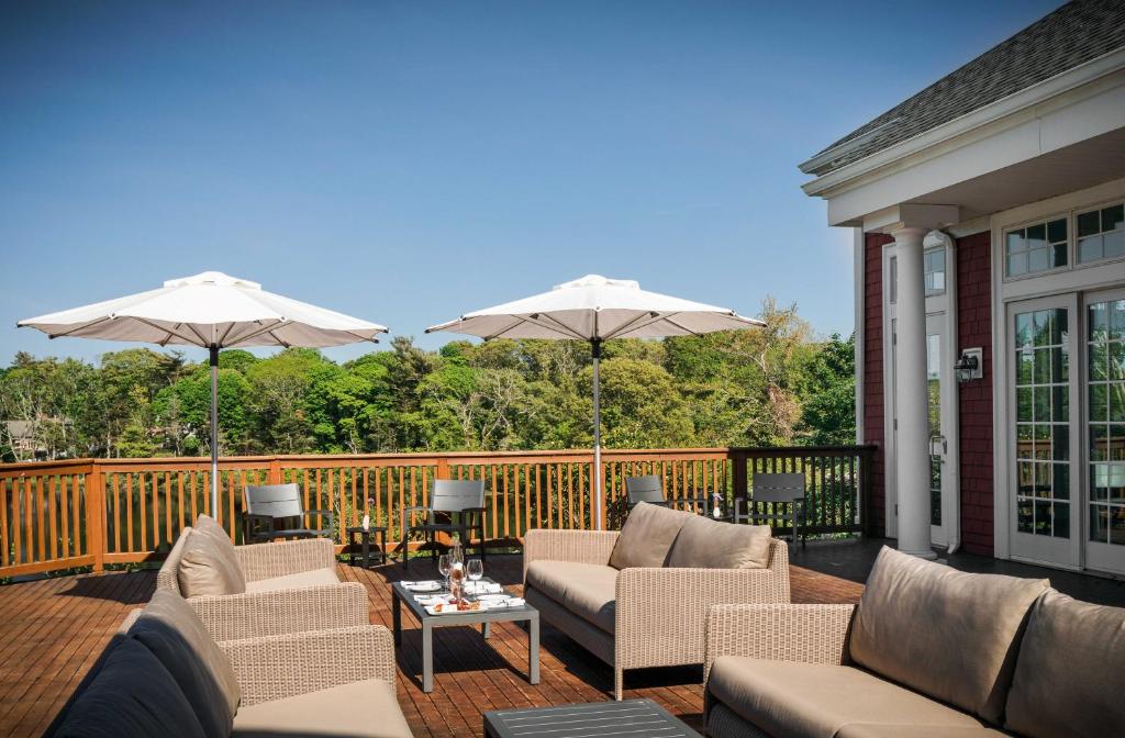 a patio with couches and umbrellas on a deck at The Coonamessett in Falmouth