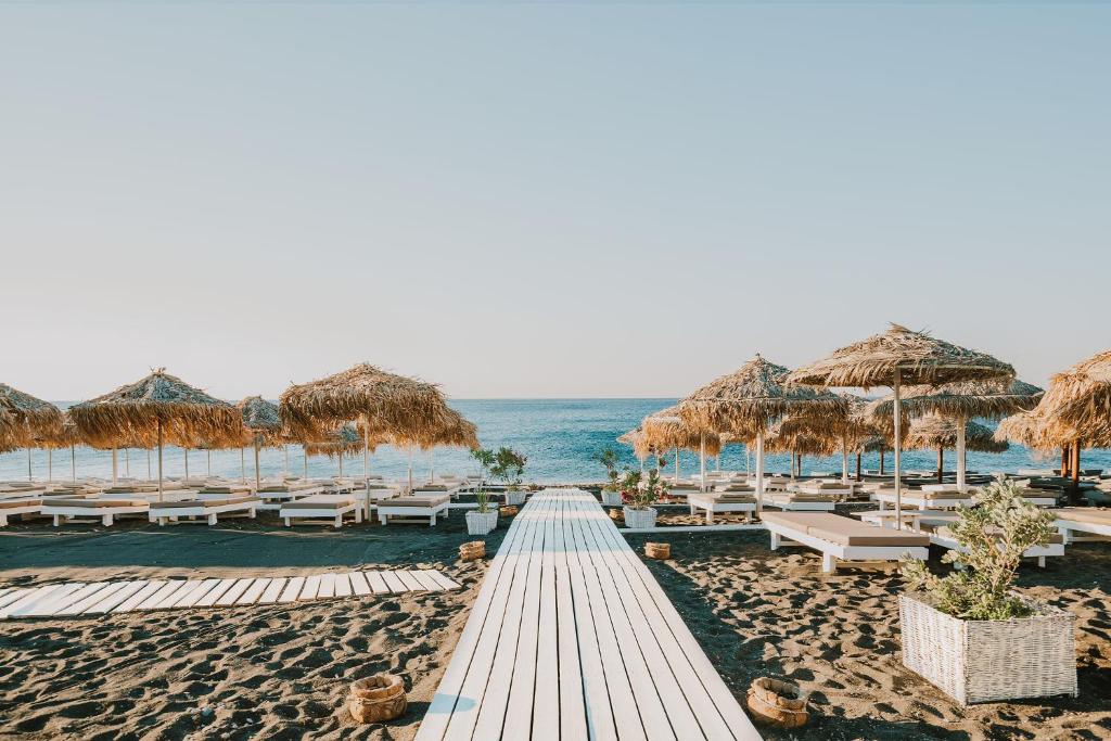 ペリヴォロスにあるSea View Beach Hotelの海沿いのビーチ(わら製のパラソル、椅子付)
