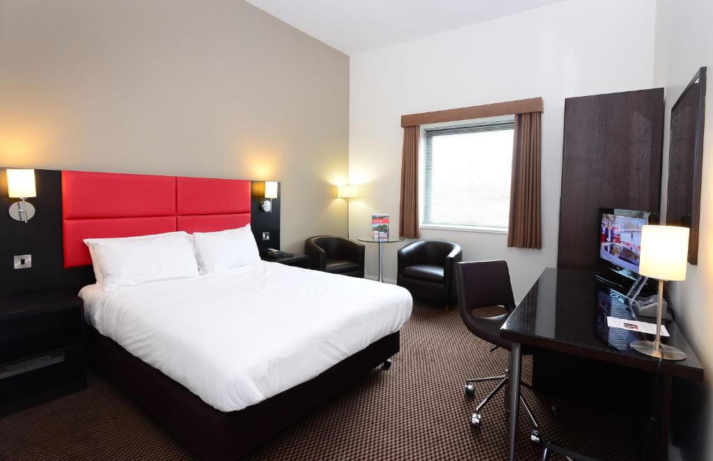 a hotel room with a bed with a red headboard at International Hotel Telford in Telford