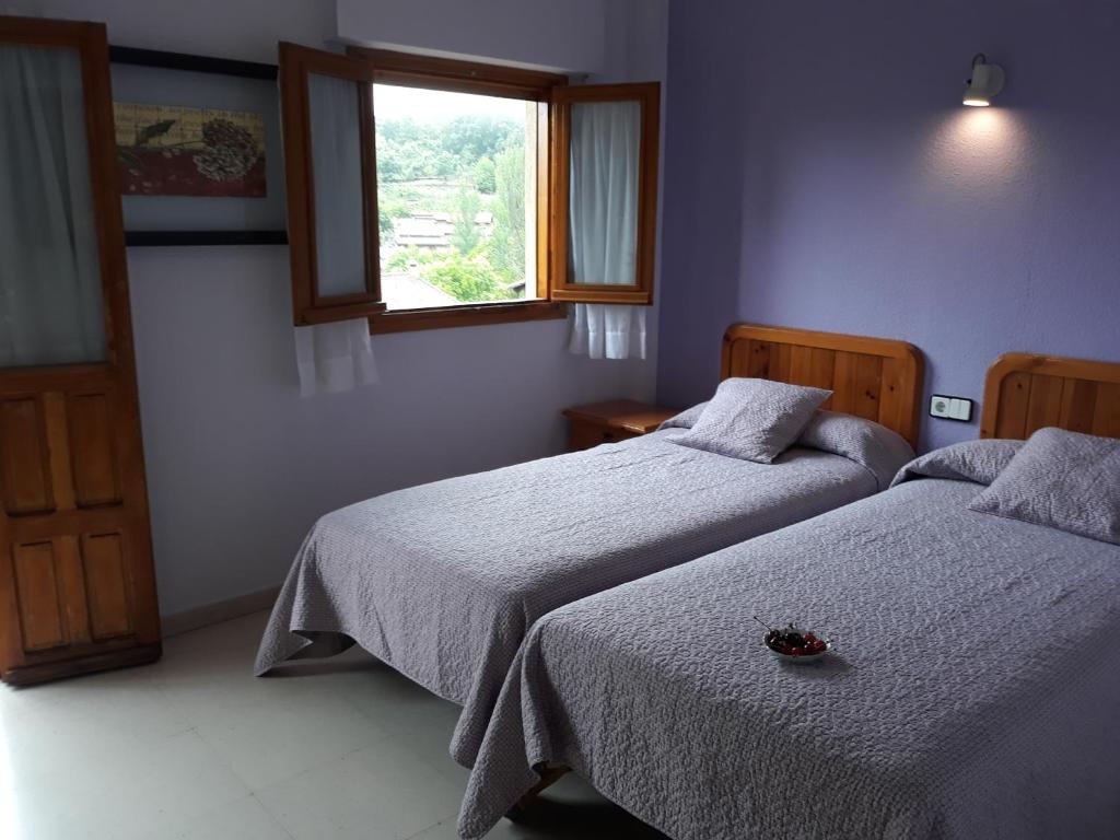 two beds in a room with a window and two beds sidx sidx sidx at Hostal Rural El Campito in San Martín del Castañar