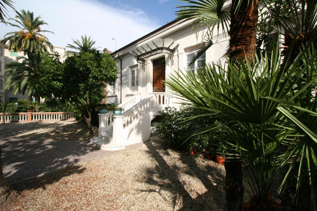una casa blanca con palmeras delante en Suites Loft La Nasse, en San Remo